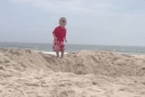 kid jumping into sand at beach